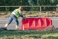 Road worker pushes red road plastic block