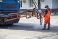 Road worker repairing asphalt coating, using a manipulator. Pitching with hot asphalt injection