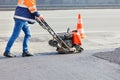 A road worker during road repair compaction of asphalt with a petrol vibratory plate compactor
