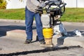 The road worker holds a bouncing vibratory rammer when repairing the roadway