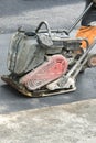 Road workers compact the asphalt with a vibrating rammer on the road. Worker with compactor at a road construction site. vertical