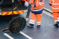 road workers and his truck cleaning the sewers on a road