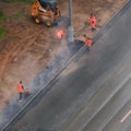 Road workers lay asphalt on the wet sidewalk during the rain - Moscow, Russia, may 21, 2020