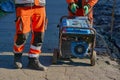 Road workers prepare to start a generator with a starter actuator cord Royalty Free Stock Photo