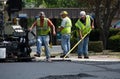 Road workers raking hot asphalt