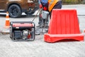 Road workers are repairing the carriageway of a section of the road with an electric jackhammer fenced with a red road shield