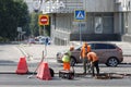 Road workers with a shovel and pneumatic hammer drill equipment repairing street during roadworks