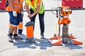 Road workers in reflective raincoats drill asphalt with a core drill