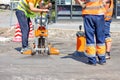 Road workers use a core drilling machine to take cores from an asphalt pavement during road repairs