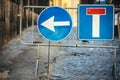 Road works detour road signs. Dead end road and arrow to turn left. Iron crossing barrier. Street with paving cobblestones Royalty Free Stock Photo