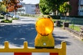 Road works. Red and white striped road caution sign with yellow flasher