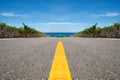 Road with yellow line ending in tropical sea