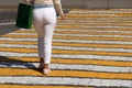 Woman in white pants walking on pedestrian crossing, rear view