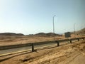 The roadside, the highway with asphalt in the desert with sand, bumpers and lampposts, sand dunes, hills in a hot tropical country Royalty Free Stock Photo