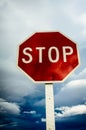 Roadside red stop sign on a cloudy background.