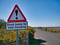 A roadside sign warns that the road ahead may be flooded at high tide Royalty Free Stock Photo