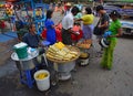 Roadside vendors selling sweet corn, cut red watermelon and vegetarian fritter