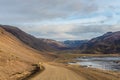 Roadtrip in Iceland dirt road in west iceland winding down into fjord during sunny weather Royalty Free Stock Photo