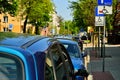 Roadway and parking cars under trees, bright sun above.