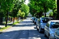 Roadway and parking cars under trees, bright sun above.