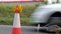 Roadworks cone flashing on UK motorway at evening with traffic passing Royalty Free Stock Photo