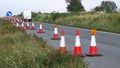 Roadworks cone flashing on UK motorway at evening with traffic passing Royalty Free Stock Photo