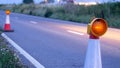 Roadworks cone flashing on UK motorway at night with traffic passing