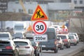 Roadworks warning traffic signs of construction work on city street and slowly moving cars Royalty Free Stock Photo