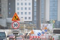 Roadworks warning traffic signs of construction work on city street and slowly moving cars Royalty Free Stock Photo