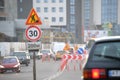 Roadworks warning traffic signs of construction work on city street and slowly moving cars Royalty Free Stock Photo