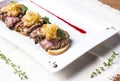 Roast beef with fried onions on pieces of baguette on white plate Royalty Free Stock Photo