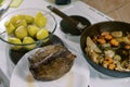 Roast beef lies on a plate next to a pan with stewed vegetables and a bowl of whole baked potatoes Royalty Free Stock Photo