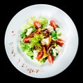 Roast beef salad with tomatoes, cucumbers, feta cheese and pepper in white plate isolated on black background. Food background, m Royalty Free Stock Photo