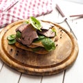 Roast beef sandwich with salad and pepper on rustic wooden plate. Royalty Free Stock Photo