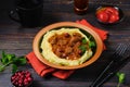 Roast beef stew with cranberries in sauce on a bed of mashed potatoes in a ceramic plate on a dark wooden background Royalty Free Stock Photo