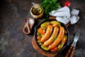 Roast Chicken sausages with potatoes, onions, carrots and mushrooms in a cast-iron pan. Top view. Royalty Free Stock Photo