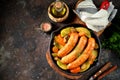 Roast Chicken sausages with potatoes, onions, carrots and mushrooms in a cast-iron pan. Top view. Royalty Free Stock Photo