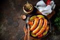 Roast Chicken sausages with potatoes, onions, carrots and mushrooms in a cast-iron pan. Top view. Royalty Free Stock Photo