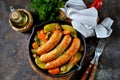 Roast Chicken sausages with potatoes, onions, carrots and mushrooms in a cast-iron pan. Top view. Royalty Free Stock Photo