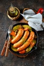 Roast Chicken sausages with potatoes, onions, carrots and mushrooms in a cast-iron pan. Top view. Royalty Free Stock Photo