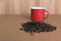 Roast coffee beans and vintage red cup on wood background Royalty Free Stock Photo