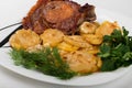 roast meat with potatoes and onions on a plate on a white background