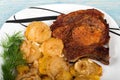 roast meat with potatoes and onions on plate, on a blue wooden background