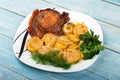 roast meat with potatoes and onions on plate, on a blue wooden background