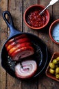 Roast pork belly roll with pepper, sea salt, dried rosemary, basil and garlic on a wooden table. Rustic style. Royalty Free Stock Photo