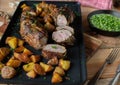 Roast pork fillet with baked potatoes and green peas on a wooden table. Royalty Free Stock Photo