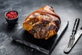 Roast pork knuckle with pink pepper and spices. Black background. Top view