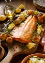 Roast salmon fillet with fresh rosemary, lemon and hasselback potatoes served on a cutting board Royalty Free Stock Photo