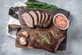 Roast and sliced tri tip beef steak on a wooden board with herbs. Gray background. Top view Royalty Free Stock Photo