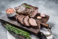 Roast and sliced tri tip beef steak on a wooden board with herbs. Gray background. Top view Royalty Free Stock Photo